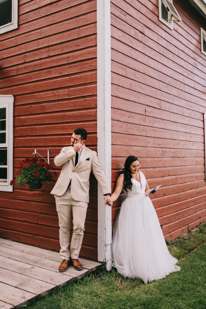 a wedding couple doing a first touch and sharing their vows at a red barn in montana in the summer